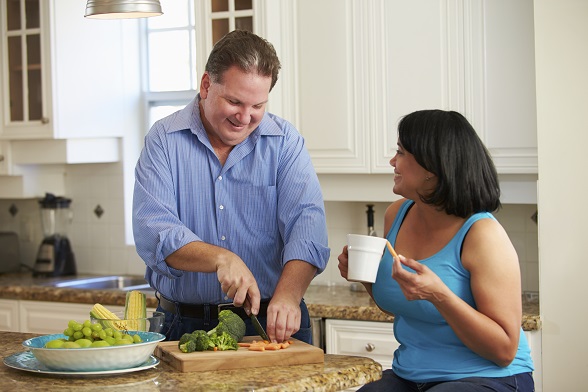 Overweight Couple Preparing Vegetables In Kitchen